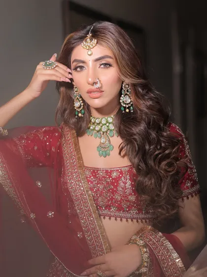 A close-up portrait showcasing the harmony between the outfit, jewellery, and makeup. The green emeralds in the Nirakara Jewels set provide a beautiful contrast against the red lehenga.