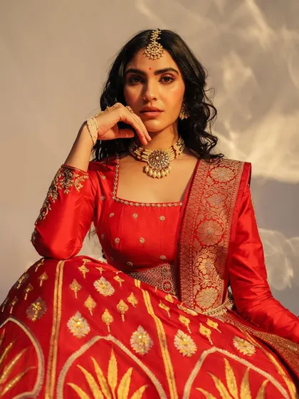 A classic red Benarasi lehenga, perfect for a bride. The combination of traditional fabric with modern styling makes it a standout piece.
