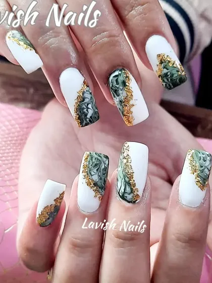 A bold design with matte white nails and a green and gold foil marble effect.
