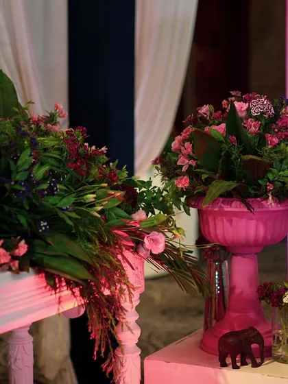 A close-up of the floral arrangements, featuring various shades of pink and lush greenery, placed in matching pink urns.