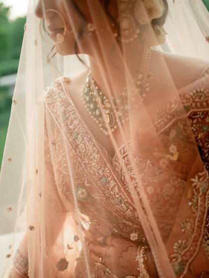 A soft and dreamy shot through the veil, highlighting the beautiful details of the jewelry and the subtle makeup.
