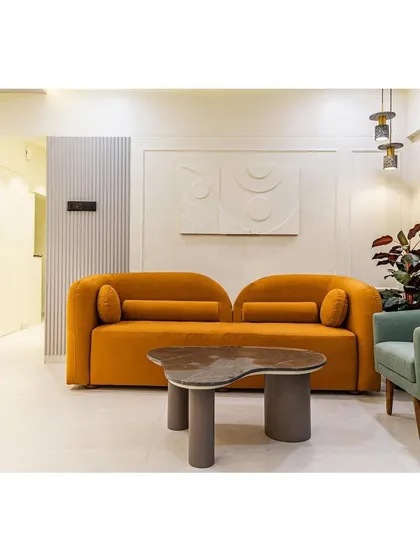 The mustard yellow sofa with its curved form is a statement piece in this living room. We paired it with a unique, sculptural coffee table and minimalist wall art.