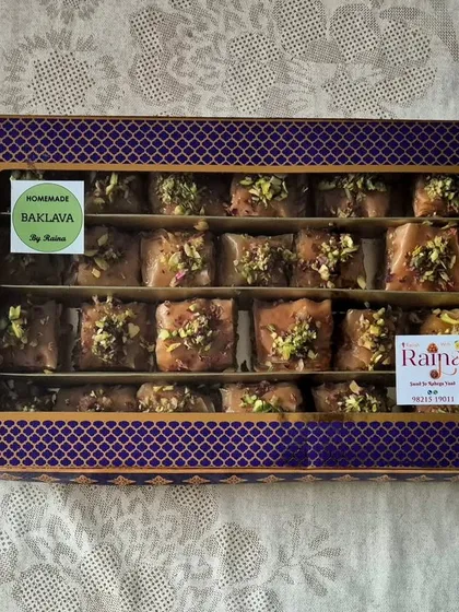 A closed gift box of Baklava, showing the elegant purple packaging with a window to see the delicious treats inside.