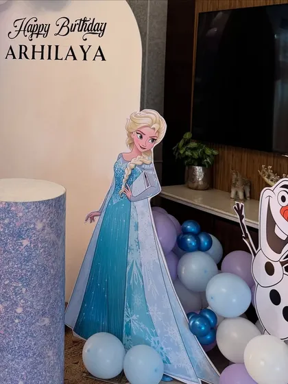 A close-up of Elsa and Olaf next to the glittery blue pedestal, ready for the birthday cake.