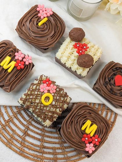 A collection of our Mother's Day brownies, each individually decorated with frosting, flowers, and letters spelling out "MOM".