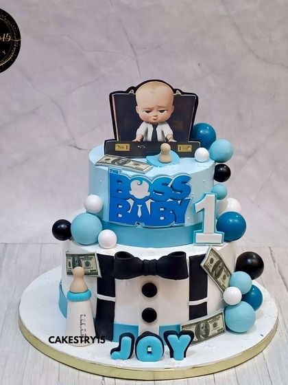 A classic two-tier Boss Baby cake for a first birthday. The 4kg chocolate cake features the signature bowtie and suit design in a stylish blue and white color scheme.