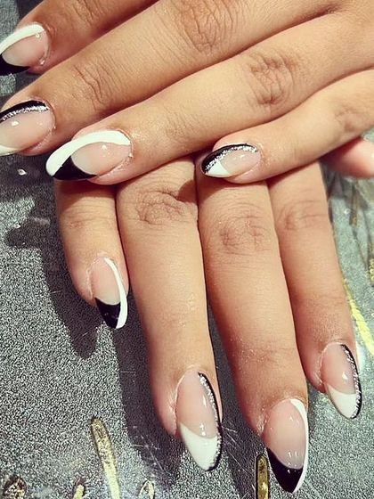 A stylish black and white French manicure on almond nails, featuring a thin line of black glitter for added definition.