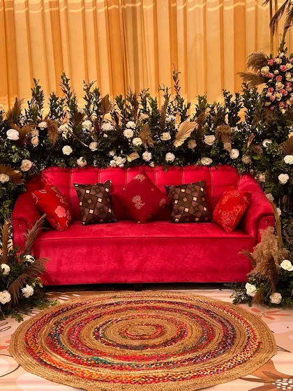 A pop of color with this red velvet sofa, surrounded by boho elements like pampas grass and a jute rug. It's a perfect blend of modern comfort and rustic charm.