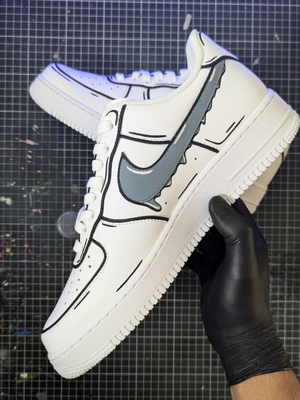 Holding up the Cartoon Drip AF1. The gray dripping swoosh and bold black lines make the shoe look like it's straight out of a comic book.