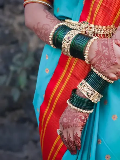 A detail-oriented shot focusing on the bride's hands, adorned with intricate henna and traditional green glass bangles (chooda), an essential part of the Maharashtrian bridal look.