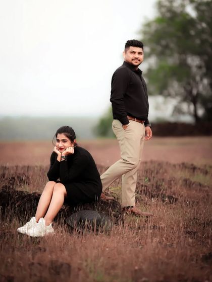 A stylish pre-wedding portrait of a couple in a field, her thoughtful pose complemented by his confident stance.