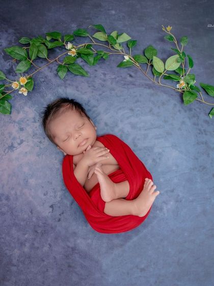 A tiny seed of love. This minimalist shot uses a bold red swaddle against a simple background, drawing all the attention to the baby's perfect, curled-up form.