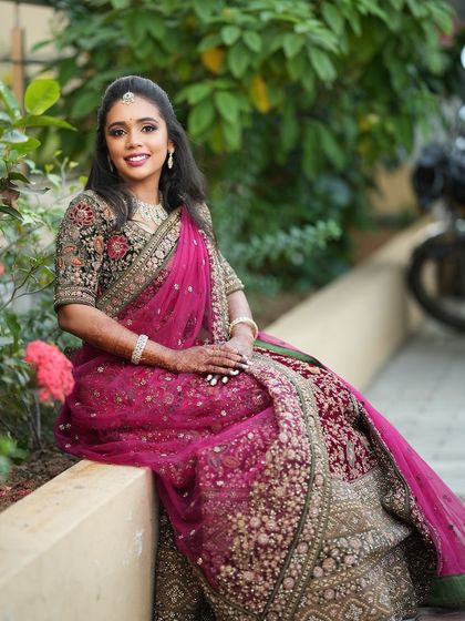 A full-length shot of Dr. Saruna seated, showcasing her magnificent embroidered lehenga. Her makeup and hair complete this stunning reception look.
