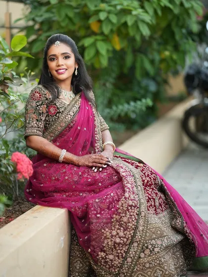 A full-length shot of Dr. Saruna seated, showcasing her magnificent embroidered lehenga. Her makeup and hair complete this stunning reception look.