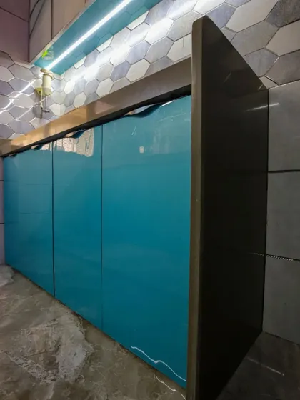 A detail shot of the glossy teal cabinets during installation, set against a hexagonal tile backsplash.
