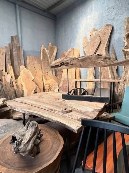 A collection of raw, live-edge wood slabs in my workshop. I source quality wood like teak and ashwood, and each piece has a unique grain and character that I try to preserve in the final furniture.