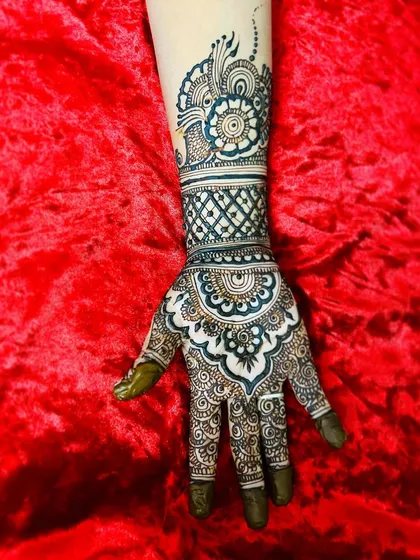 A single hand adorned with a heavy, intricate design. The combination of a mandala, jaal pattern, and bold cuff creates a very rich and traditional look.