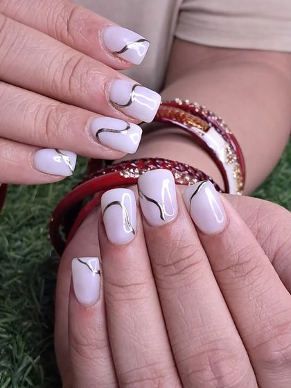 Another view of the elegant milky white and gold line art nails.
