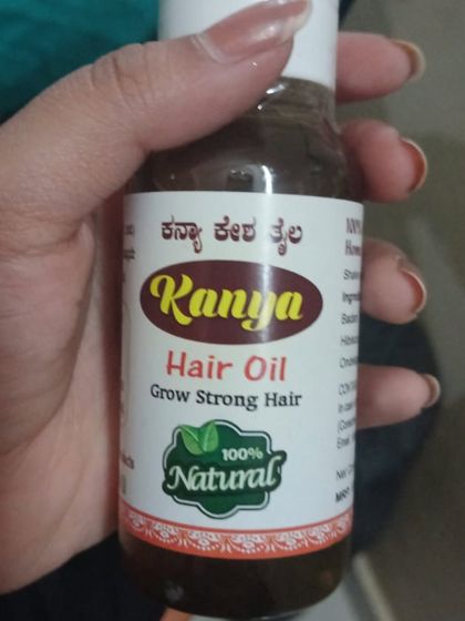 A close-up view of the Kanya Hair Oil label, showing the "100% Natural" seal of quality.