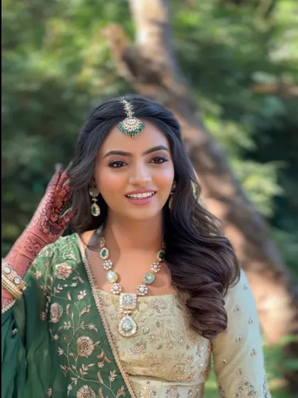 A classic half-up hairstyle with a center part and soft waves, perfect for framing a maang tikka and creating a timeless bridal look for an outdoor wedding.