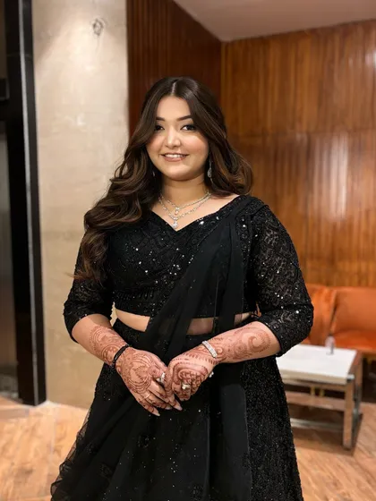 The full look. The client looks absolutely stunning and ready for her party. The all-black outfit is the perfect canvas for glowing makeup.