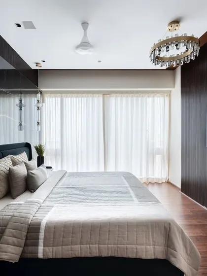 This luxury master bedroom redefines elegance with opulent wooden finishes and a striking black book-matched marble backsplash. The design includes a cleverly hidden walk-in wardrobe door within the fluted paneling, creating a tranquil and cozy yet lavish sanctuary.