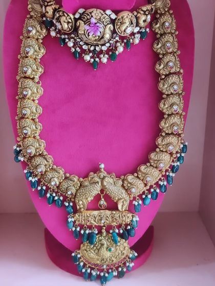 An antique gold finish choker and haram set with peacock motifs and blue bead drops.