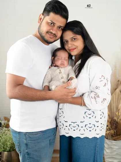 The whole family together, holding their greatest blessing. The coordinated white outfits create a clean and serene look for this first family photo.