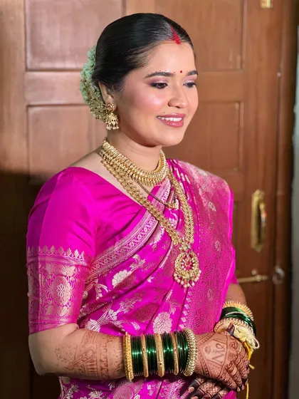 A side profile showing the traditional sleek bun adorned with fresh gajra. The makeup is kept clean and elegant to highlight these beautiful cultural details.