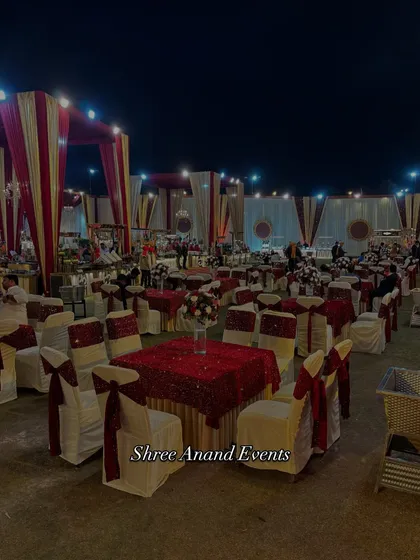 An overview of the guest dining area at an outdoor wedding. The tables are elegantly set with red and white linens and chair covers, creating a classic and formal atmosphere for the reception.