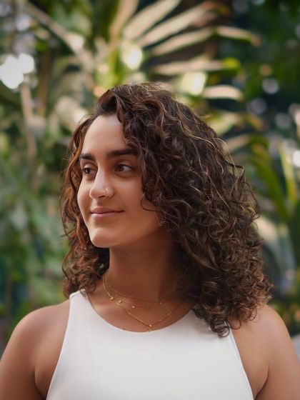 Waves of wonder. This client's naturally curly hair is enhanced with subtle highlights and a shaping cut to create this beautiful, beachy look.