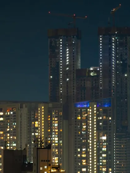 The crescent moon hangs in the night sky next to a pair of towering, under-construction skyscrapers in Mumbai.