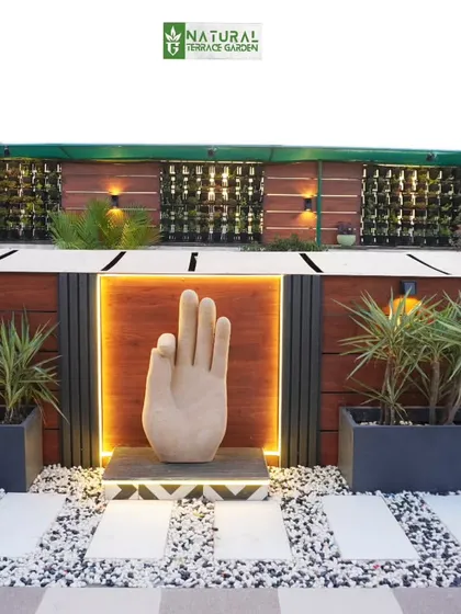 A unique hand sculpture with backlighting, creating a striking and modern art piece in this Palam Vihar garden.