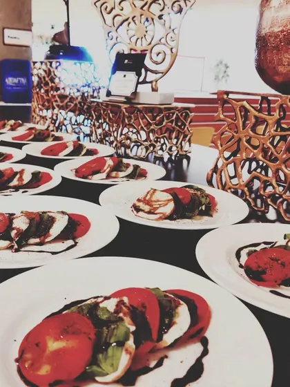 Our classic Caprese Salad, plated and ready to be served. Made with fresh mozzarella, ripe tomatoes, and fragrant basil, and drizzled with a balsamic glaze, it's a simple yet elegant choice.