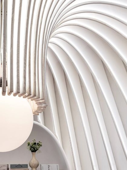 A close-up view looking up at the illuminated curves of the fabric fins and the custom chandelier. This detail showcases the precision and artistry involved in turning a soft material like fabric into a structural and sculptural element.