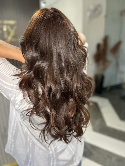 Beautifully styled brunette hair with soft, flowing waves that showcase its health and shine.