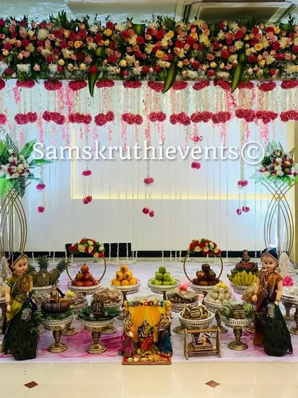 A beautiful baby shower setup with a floral arch of pink and white roses. The hanging carnation strings and an elaborate display of offerings create a delicate and sophisticated look for the mother-to-be.