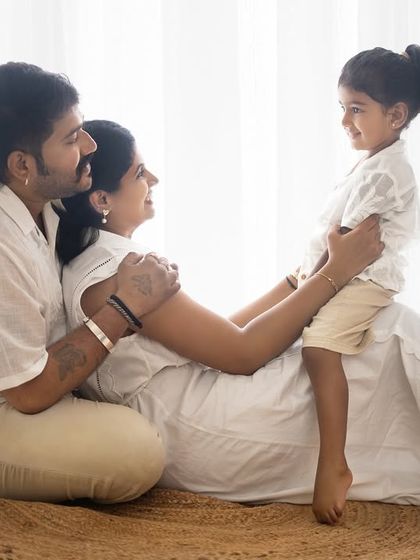 A lovely, interactive family moment on the floor. The focus is on the connection between the parents and their child.