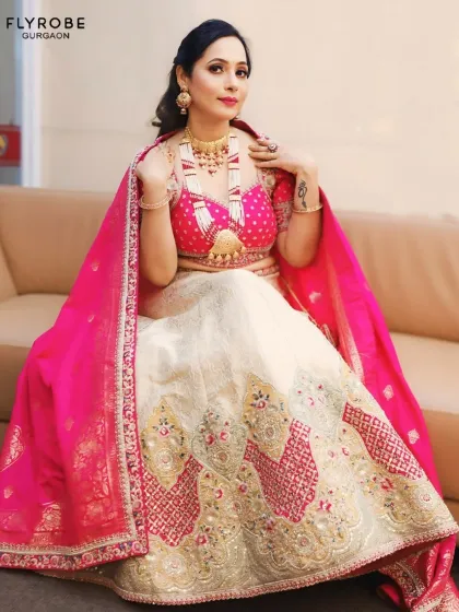 This unique white and pink lehenga with a statement blouse is for the fashion-forward wedding guest. The heavy gold jewellery completes this royal look.