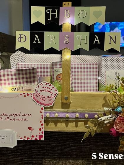 The full view of a '5 Senses' hamper created for a birthday. It includes a personalized 'HBD DARSHAN' banner and photos, making it a one of a kind gift.