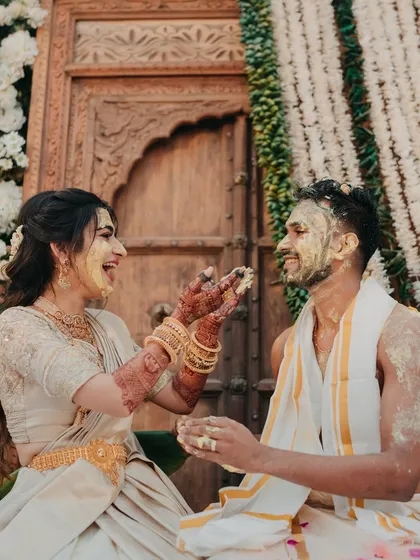 Another joyful shot from the South Indian Haldi, capturing the couple's laughter as they get covered in turmeric. These candid moments are the essence of a great wedding album.