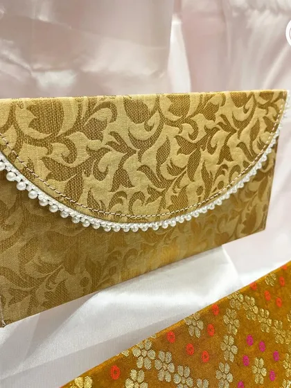 Custom wedding envelopes in a traditional gold brocade fabric, finished with a delicate pearl trim.