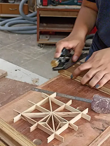 Using a block plane to make fine adjustments to the Kumiko pieces. This level of detail ensures that every joint is seamless and the final pattern is flawless.