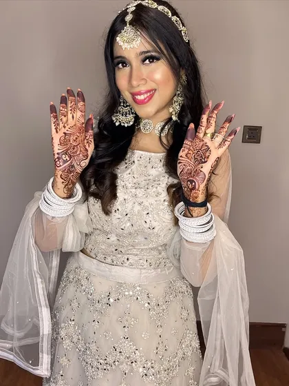 A fun pose showing off her beautiful henna. The makeup is bold enough to balance the traditional elements of her look.