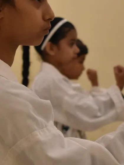 Female students hold a strong ready stance during their grading, showing focus and determination.