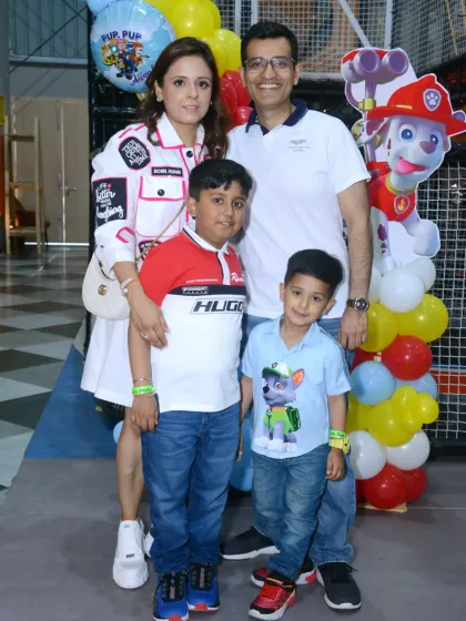 A happy family photo at a Paw Patrol party. The themed decorations, including a Marshall cutout, make for a memorable celebration.