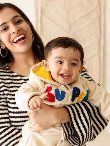 A mother and her one-year-old son share a laugh in a candid moment from a family session.