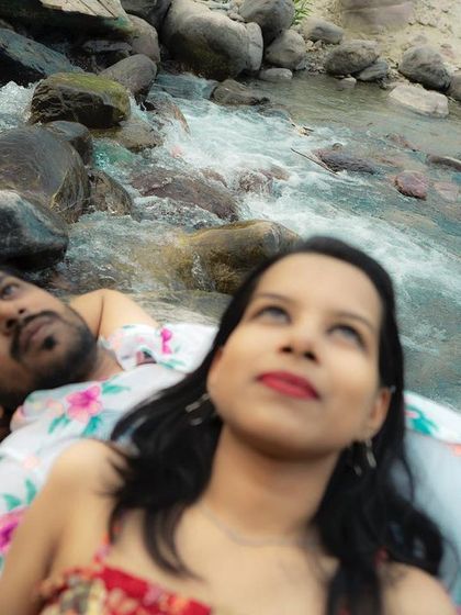 A creative top-down angle of the couple looking up, with the flowing river as a dynamic background for their pre-wedding photo.
