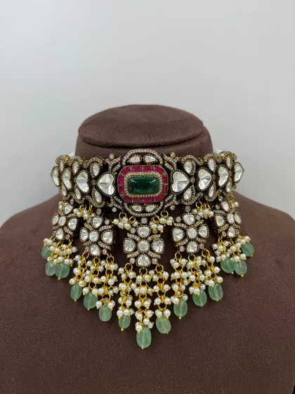 The beauty of traditional craftsmanship is in the details. This is a classic bridal choker, featuring intricate kundan work, a central emerald, and clusters of pearls and mint-green beads. It feels substantial and looks incredibly luxurious.