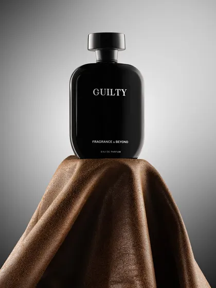 A bold, minimalist shot of a black perfume bottle on a piece of brown fabric. The simple, strong composition and lighting convey a sense of masculine sophistication and quiet confidence.